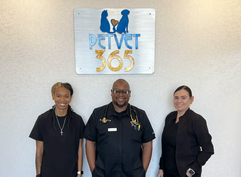 Three veterinarians standing in front of the PetVet365 sign.